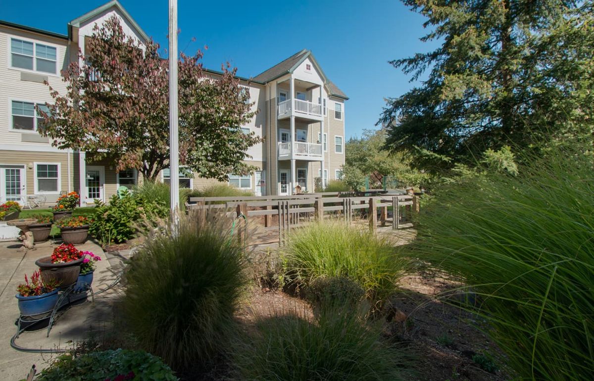 A residential apartment building surrounded by greenery and a pathway.