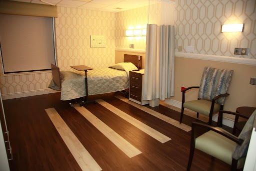 A welcoming hospital room designed for patient comfort, featuring a bed, seating area, and soft lighting.
