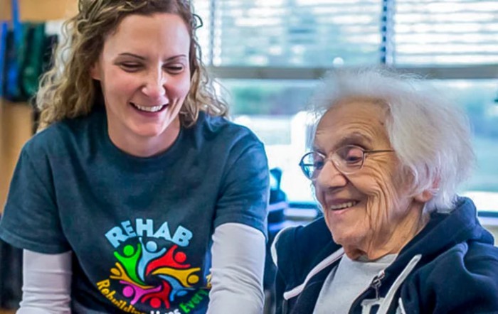 A caregiver and an elderly woman share a joyful moment together.