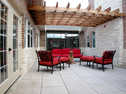 A cozy outdoor patio with red-cushioned furniture under a wooden pergola.