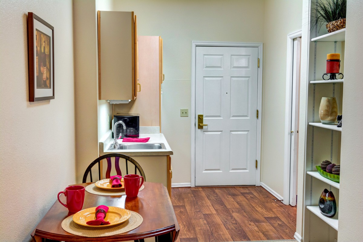 A cozy kitchen and dining area with a neatly set table and wood flooring.