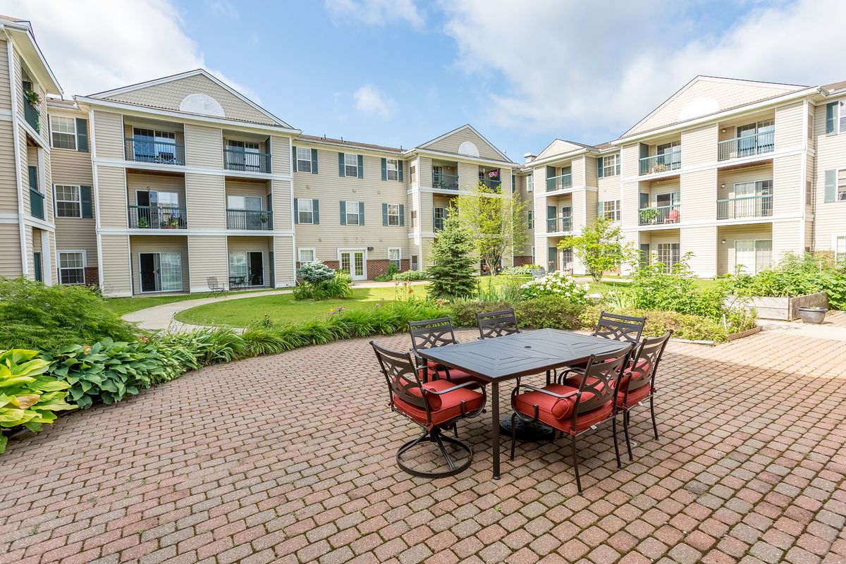 A well-landscaped courtyard with patio furniture in front of a multi-story apartment building.