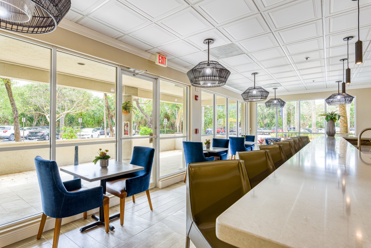 A modern and spacious cafe interior with comfortable seating and large windows.