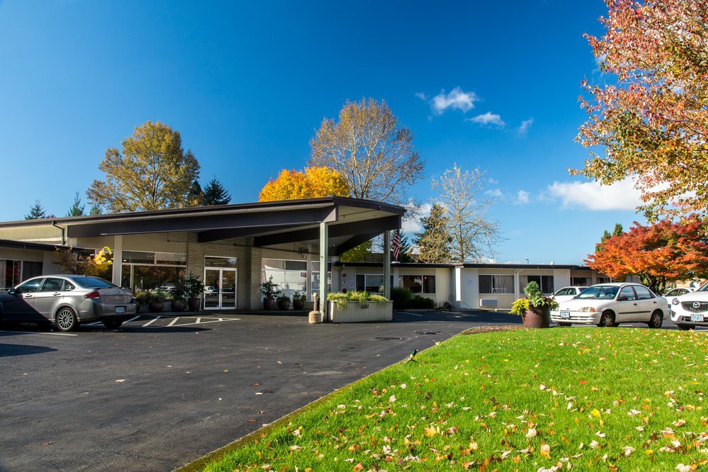 A modern building surrounded by autumn trees and a clear blue sky.
