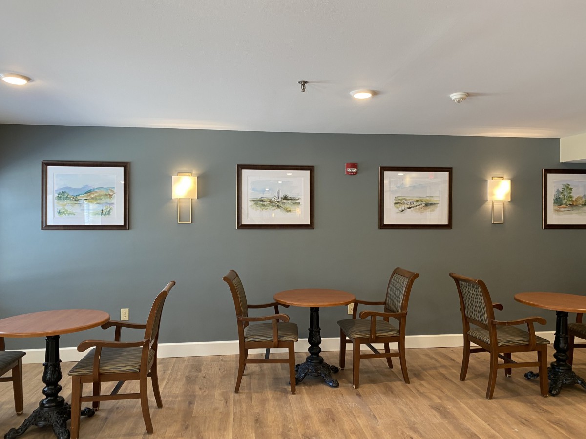 A cozy dining area with tables and chairs, decorated with wall art and warm lighting.