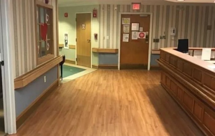 An empty hospital hallway with wooden flooring and a reception area.