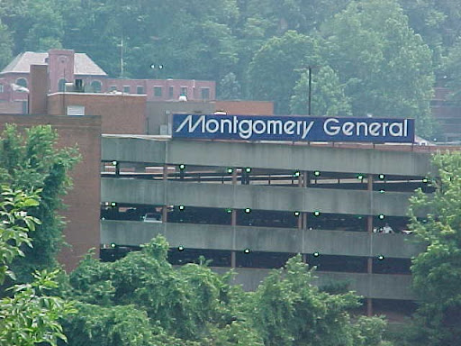 View of Montgomery General Hospital's parking structure amidst a lush green landscape.