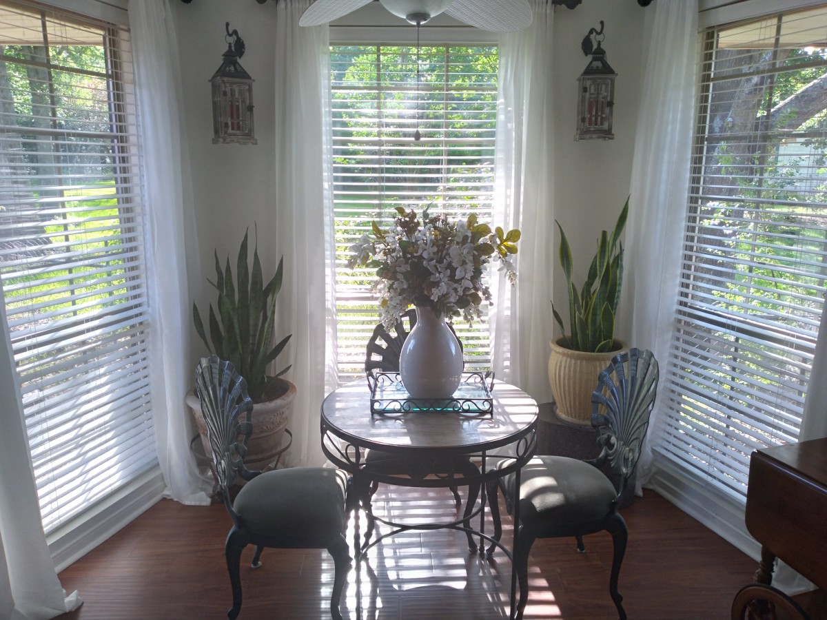 A cozy dining nook with a round table, surrounded by chairs and decorated with plants, basking in natural sunlight.