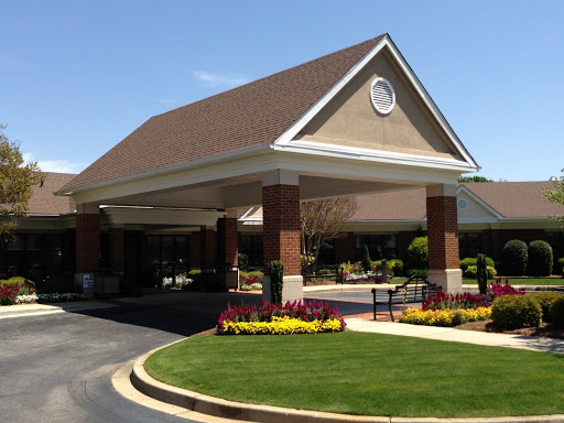 A welcoming entrance of a facility surrounded by vibrant landscaping under clear blue skies.