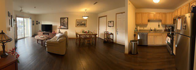 A cozy dining room with a wooden table and chairs, featuring warm lighting and a polished wooden floor.