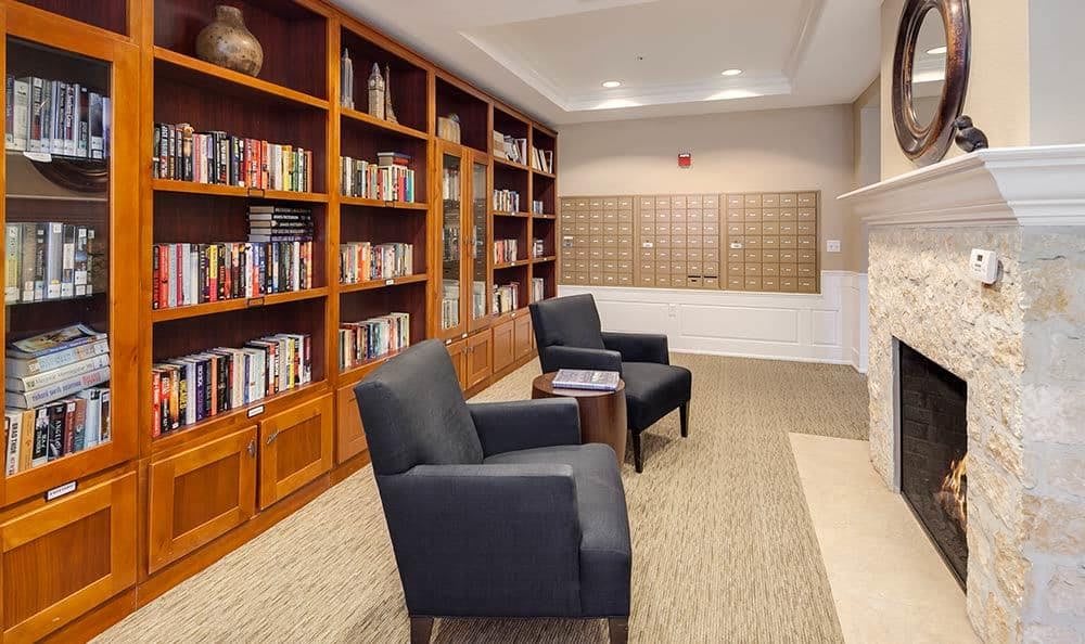 A cozy library with wooden bookshelves and comfortable chairs arranged for reading.