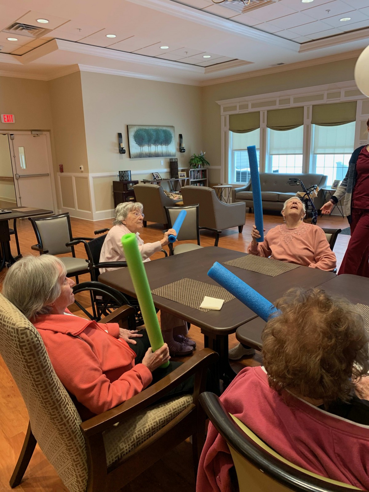 Seniors engaging in a fun activity with pool noodles at a community center.