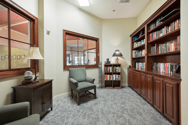 A cozy reading room with bookshelves, a comfortable chair, and soft lighting.