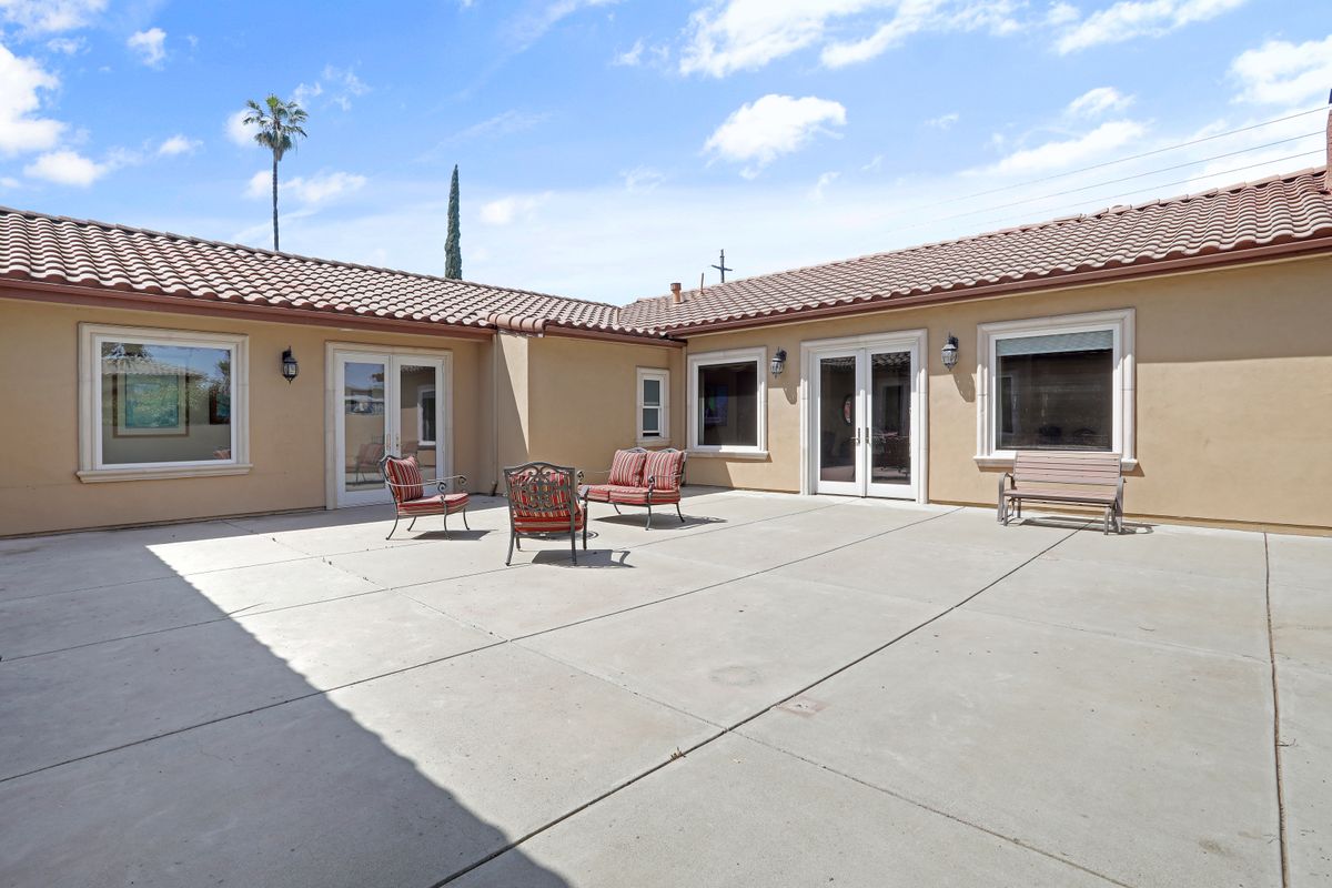 A sunny courtyard featuring outdoor furniture and a spacious patio area.