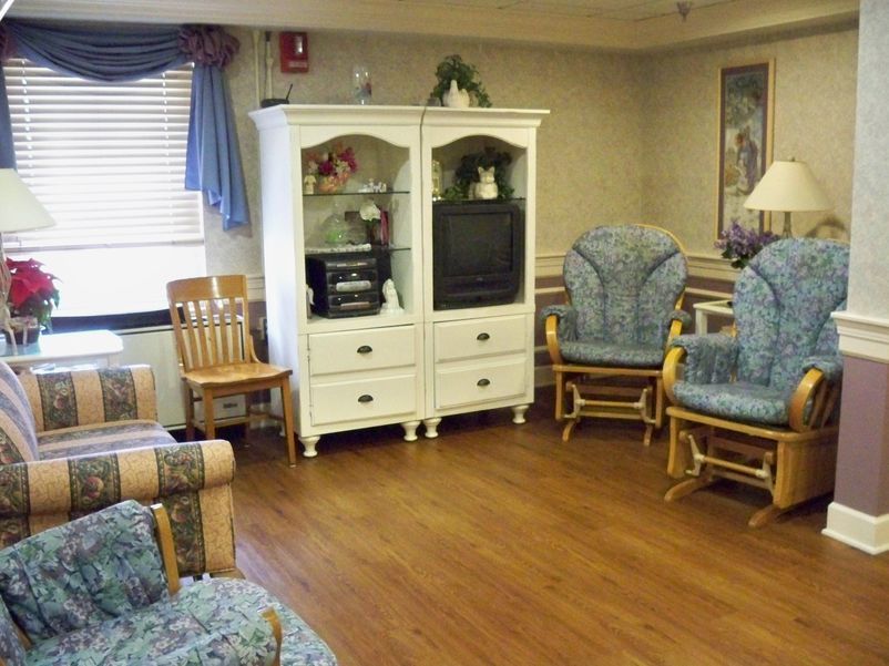 A cozy living room with a white entertainment center, rocking chairs, and wooden flooring.