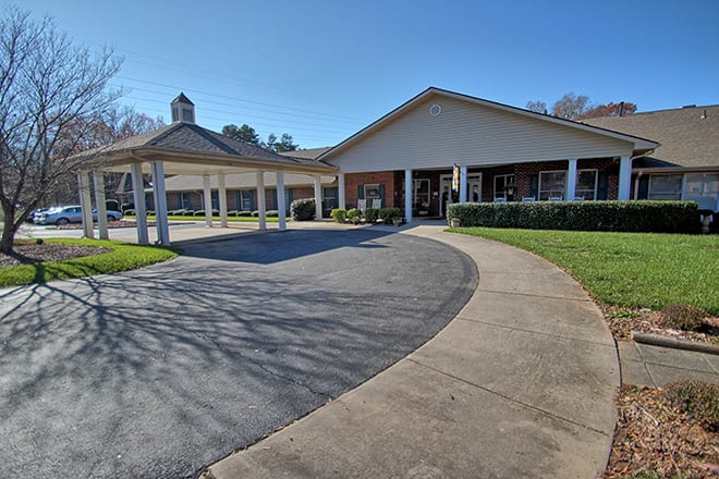 A building with a covered entrance and driveway on a sunny day.