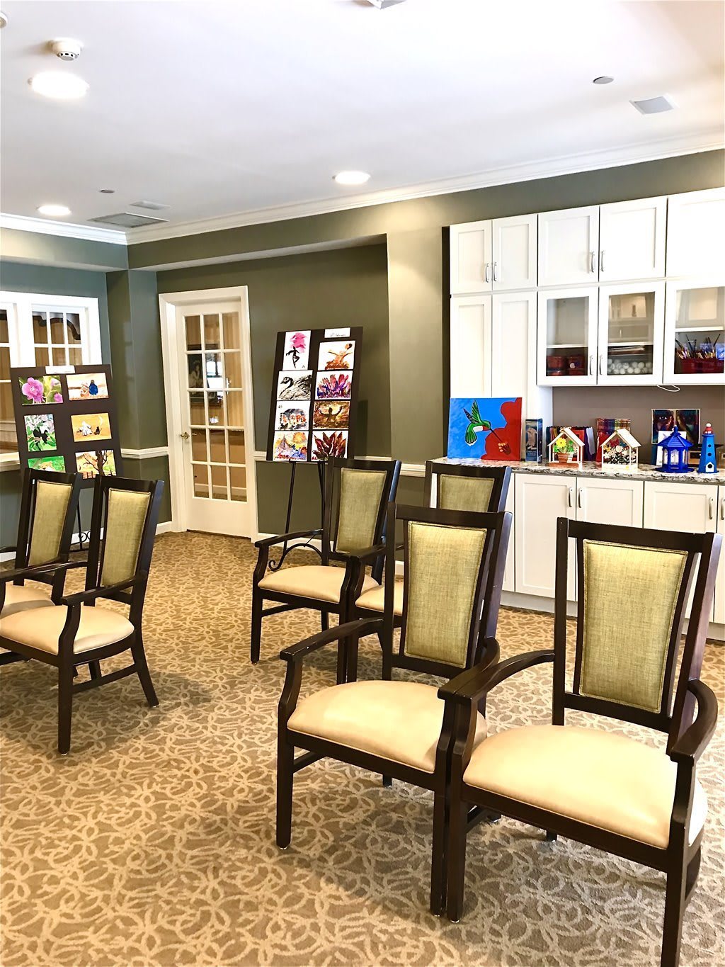 An interior room with chairs arranged in rows and art pieces displayed on the walls and tables.