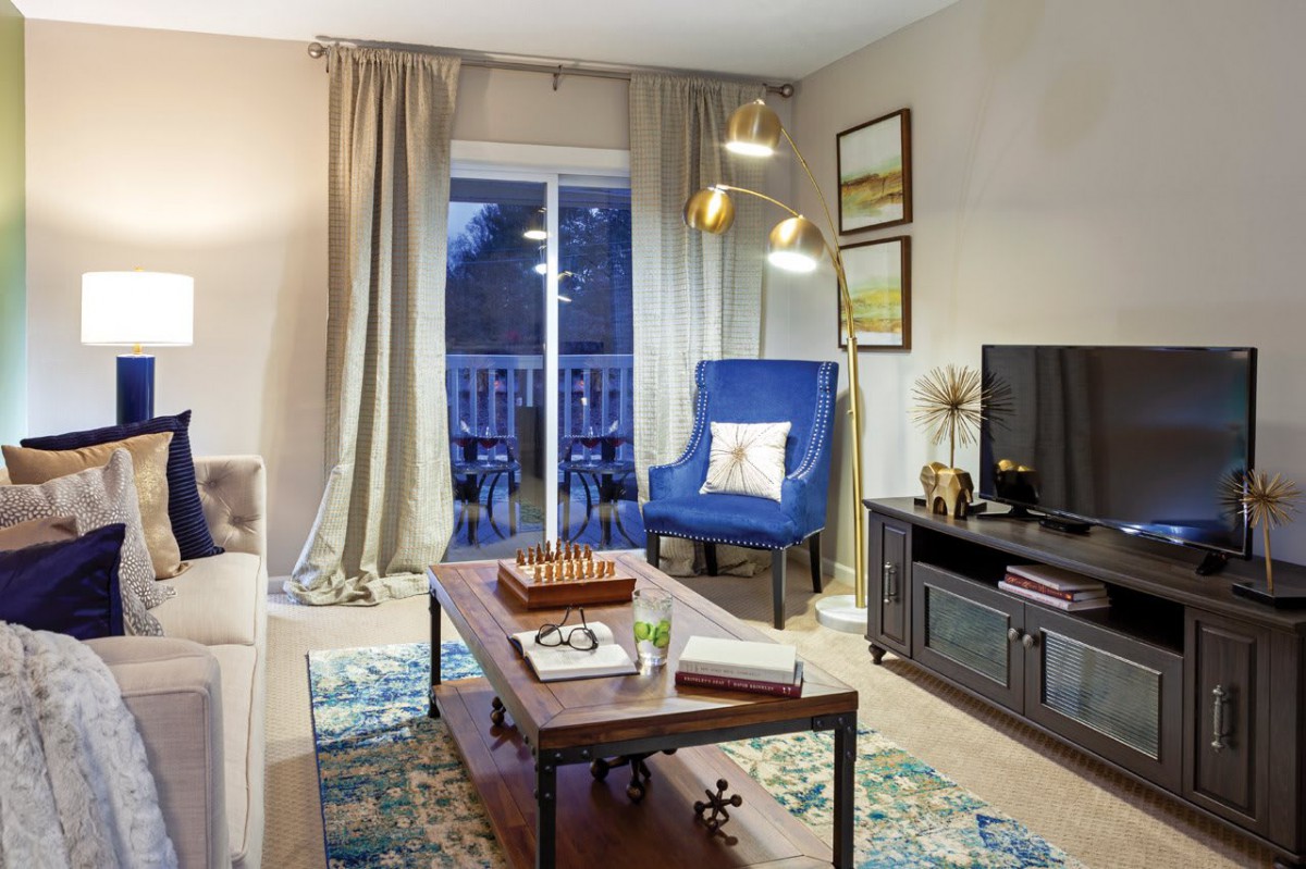 A modern and stylish living room featuring a blue armchair, decorative rug, and contemporary furnishings.