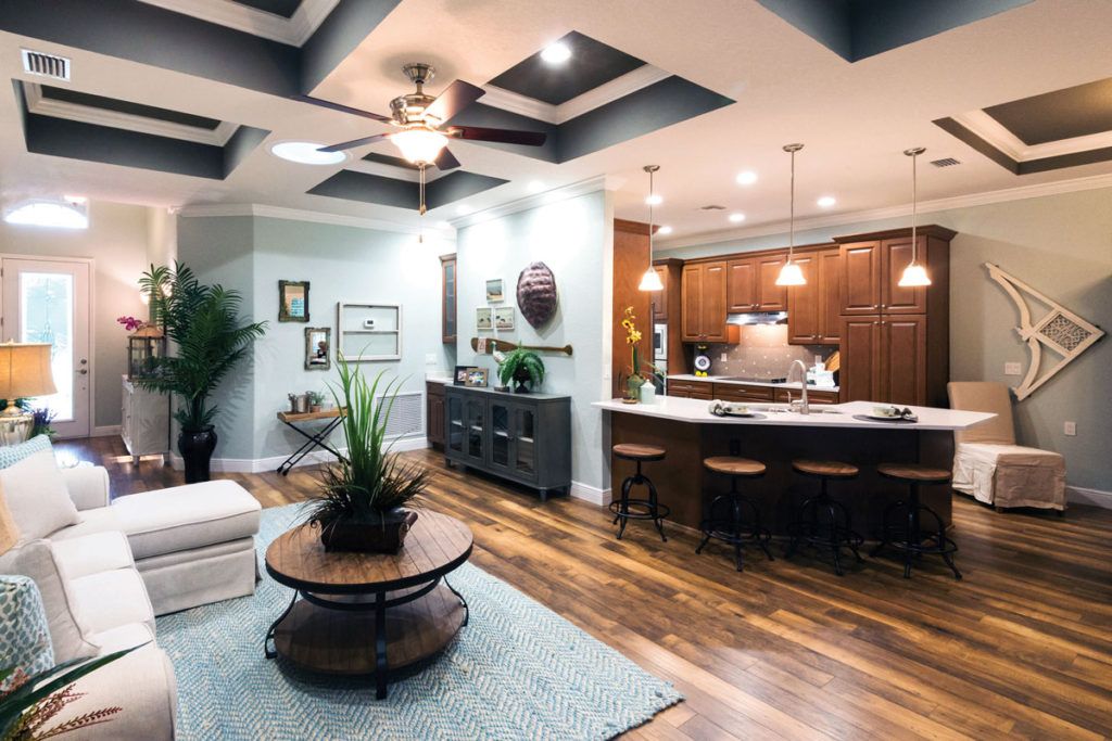 A modern open-plan living space featuring a stylish kitchen with wooden cabinets and bar stools, adjacent to a cozy living area with contemporary decor.