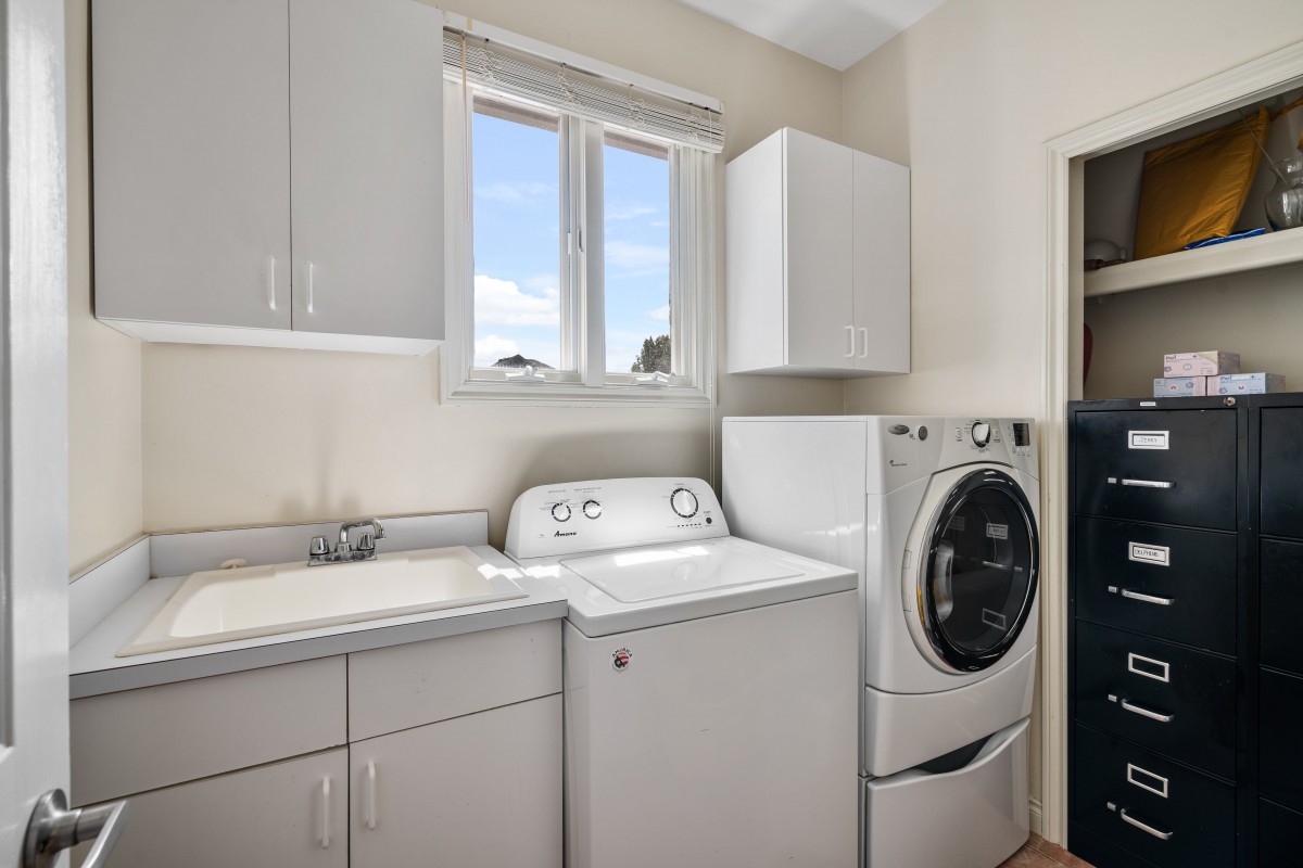 A modern laundry room featuring a washing machine, dryer, and cabinets.