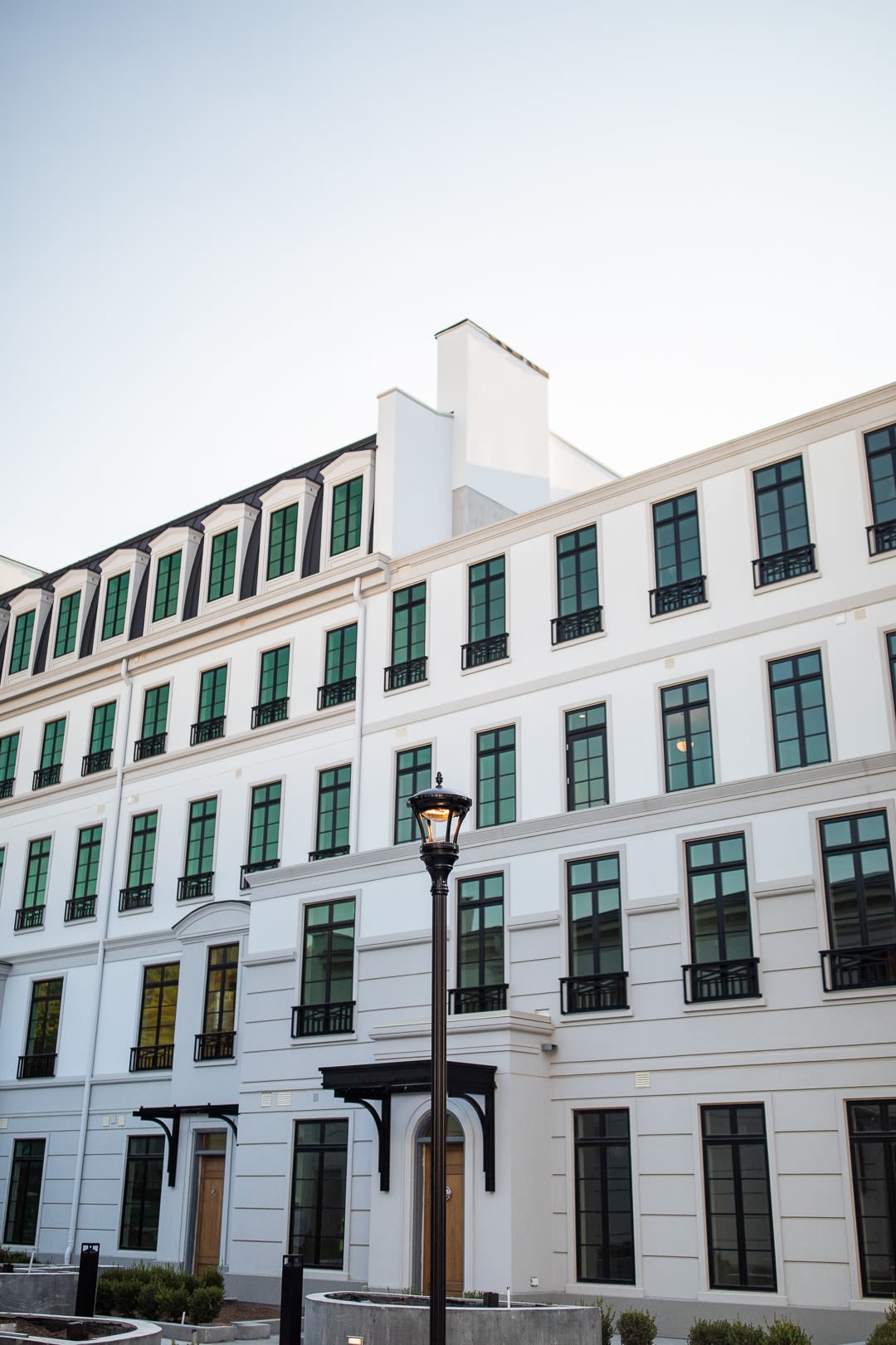 A view of a modern white building with multiple windows and a streetlamp.