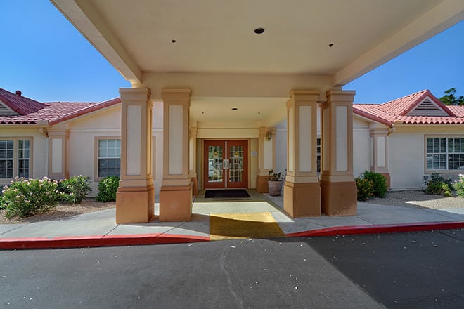 Entrance of a building with a covered walkway and columns.