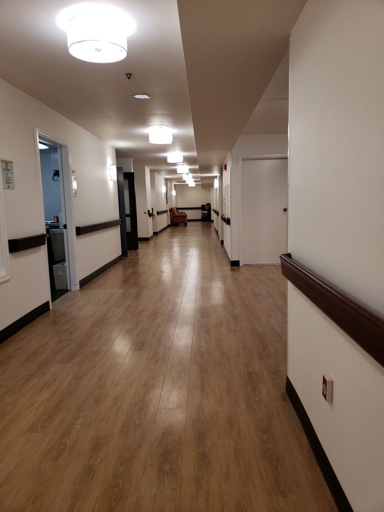 A well-lit hallway with wooden flooring and multiple doors along the sides.