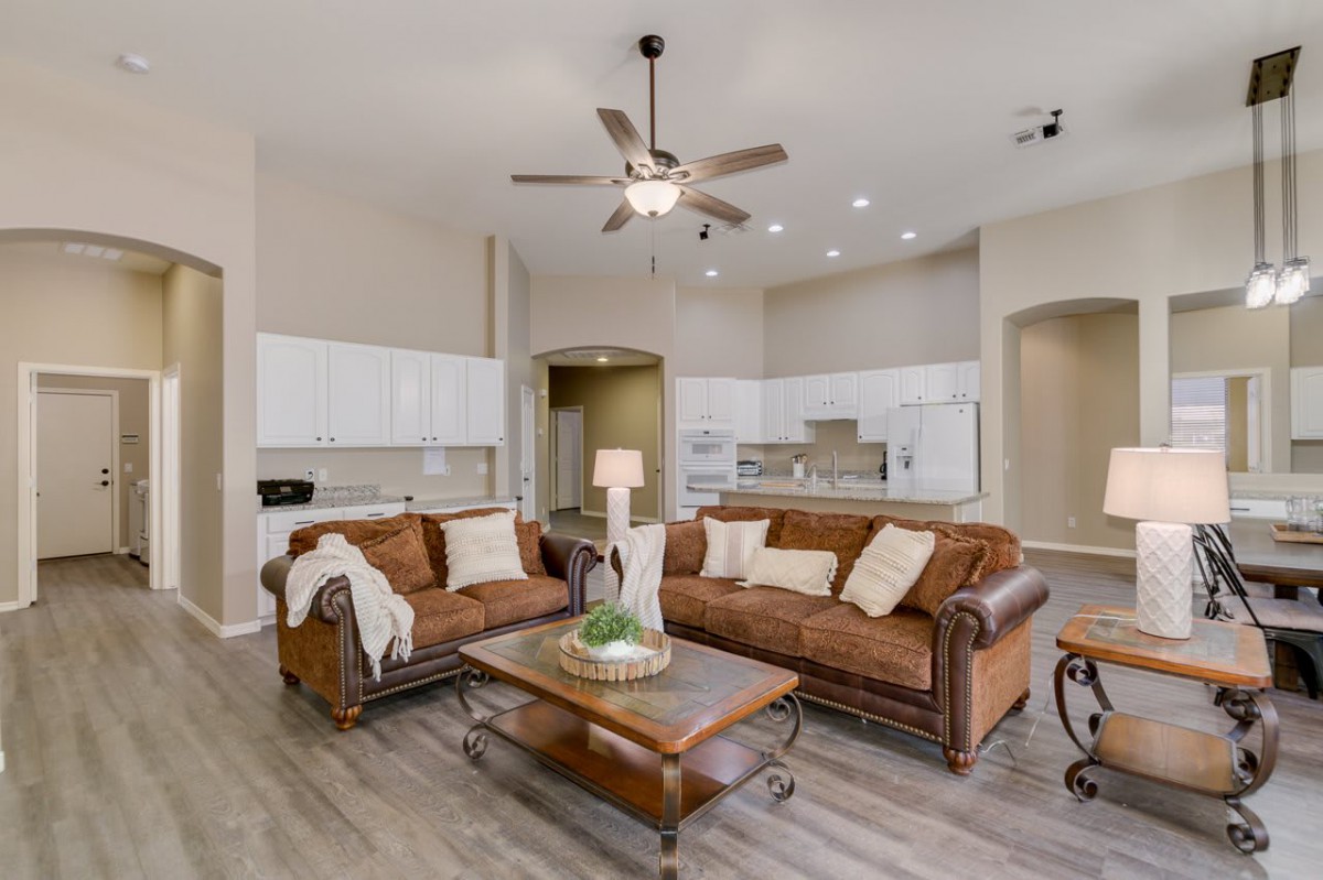 A modern open-concept living room with leather sofas and a view into the kitchen.