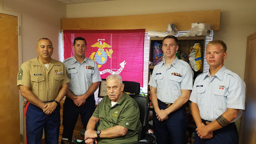 A group of servicemen posing with a veteran, showcasing respect and camaraderie.