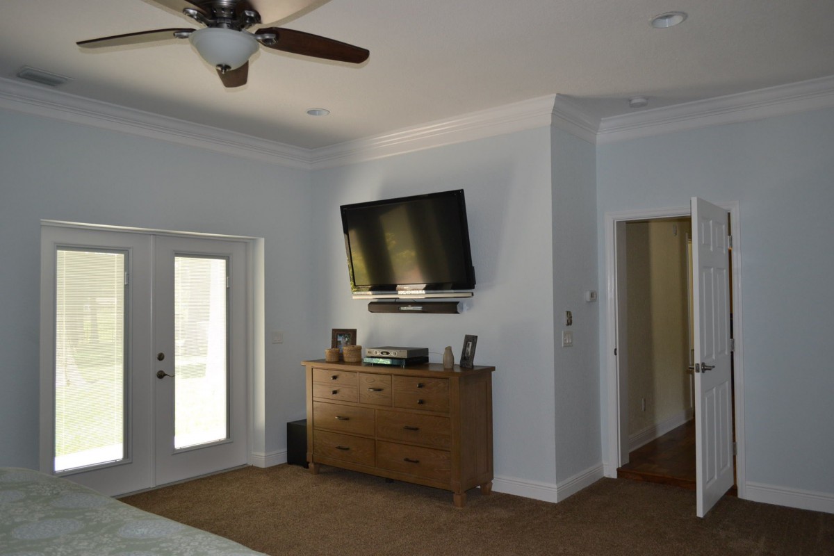 A modern bedroom featuring a wall-mounted television and a wooden dresser.