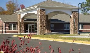 A building entrance featuring stone columns and a landscaped foreground.