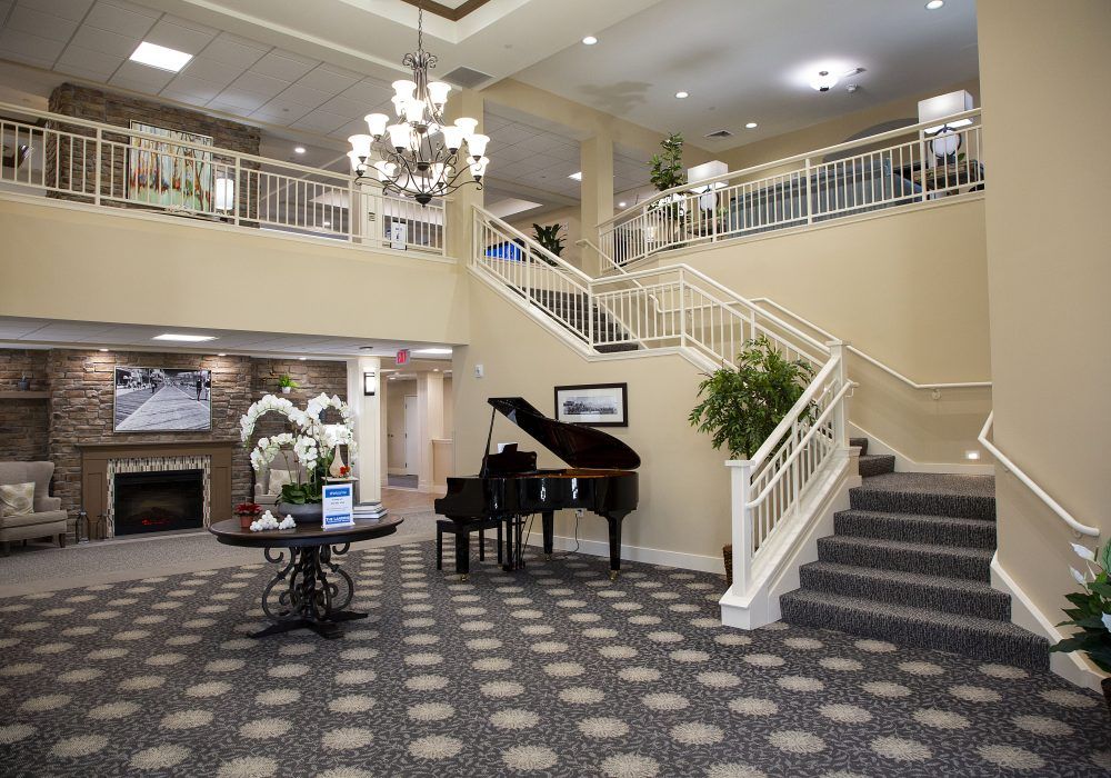 A spacious hotel lobby with an elegant staircase and a grand piano.
