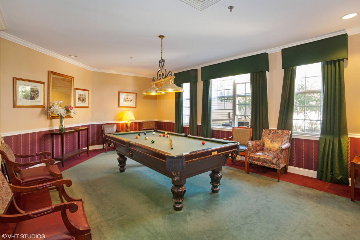 A classic billiard room featuring a pool table, elegant lighting, and traditional decor.