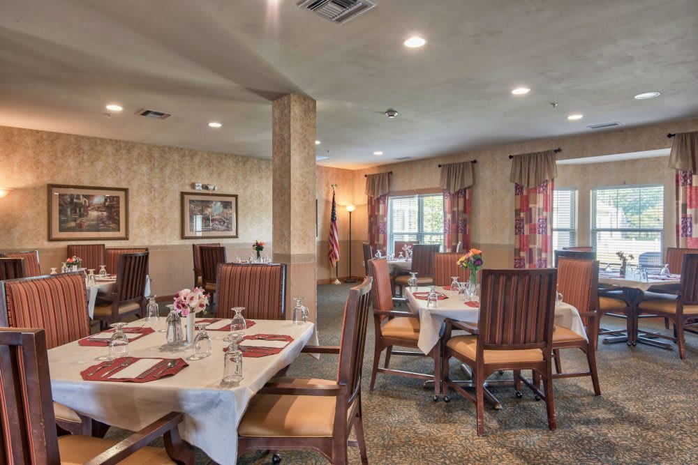 A cozy dining room with elegantly set tables and comfortable chairs, featuring warm decor and soft lighting.