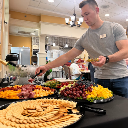 A man serves a colorful array of fruits and snacks at a buffet.