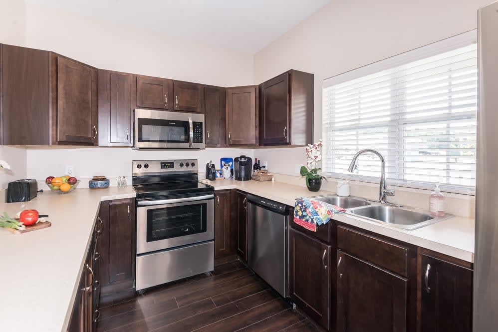 A modern kitchen with stainless steel appliances and dark wooden cabinets.