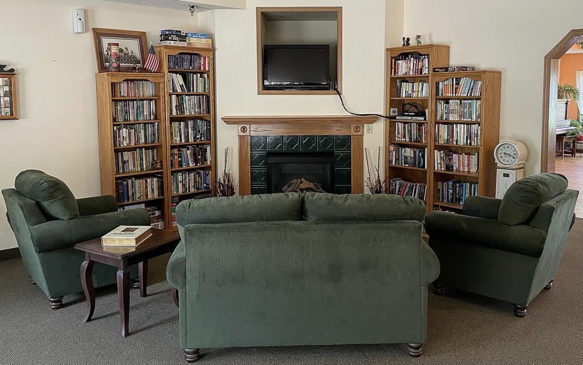 A cozy living room library with bookshelves, a sofa, and a fireplace.