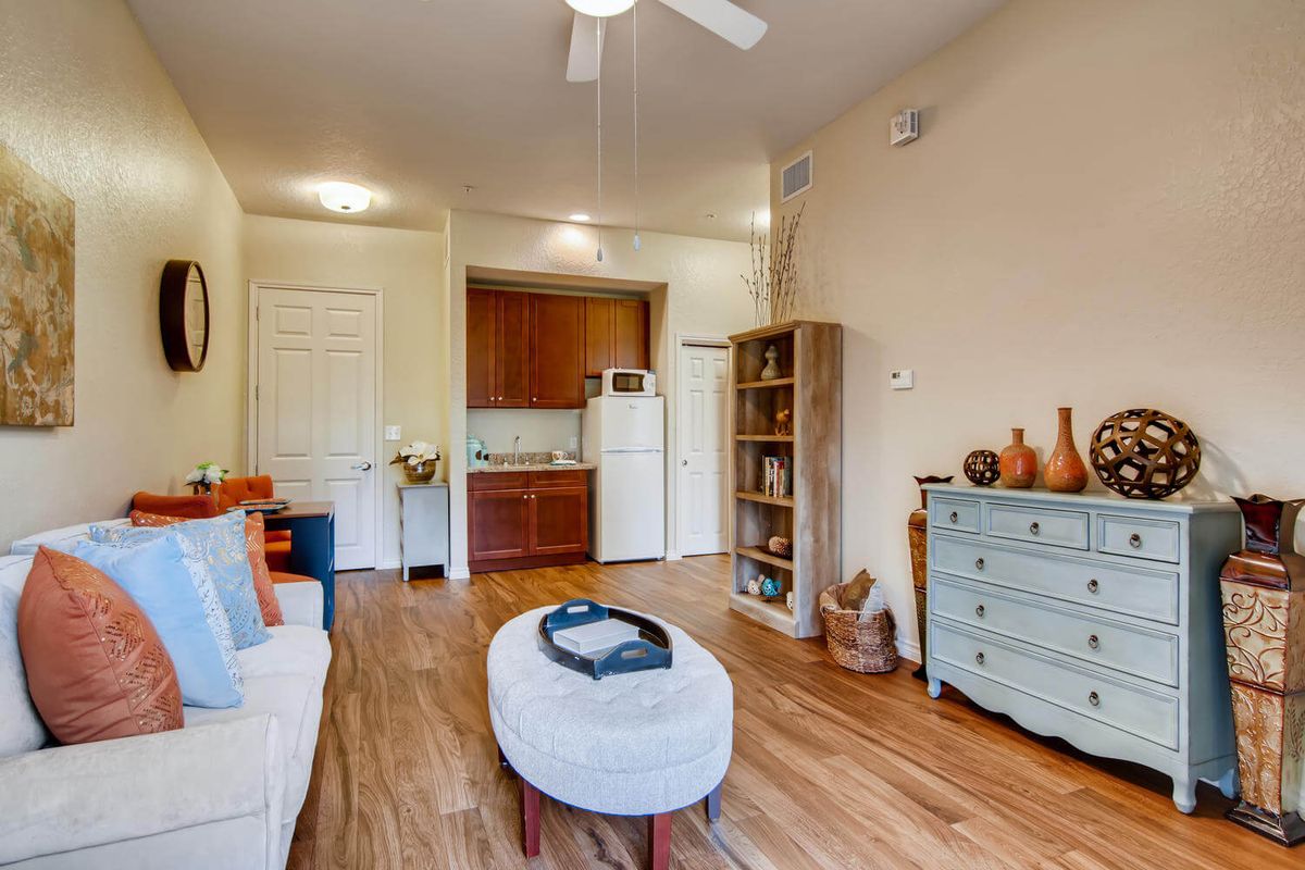 A cozy living room with modern decor featuring wooden flooring, a bookshelf, and a ceiling fan.