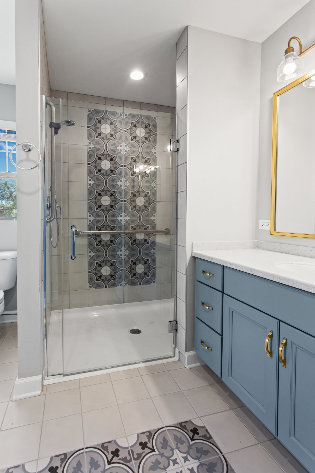 A modern bathroom with a stylishly tiled shower and a blue vanity.