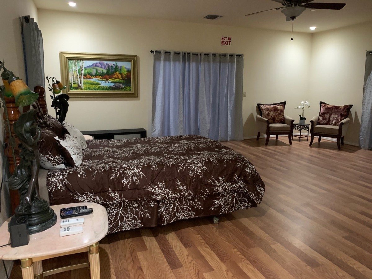 A spacious bedroom with a large bed, elegant decor, and wooden flooring.