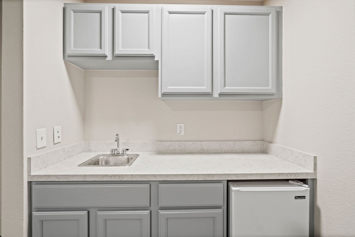 A minimalist kitchen setup with light gray cabinets and a small sink.