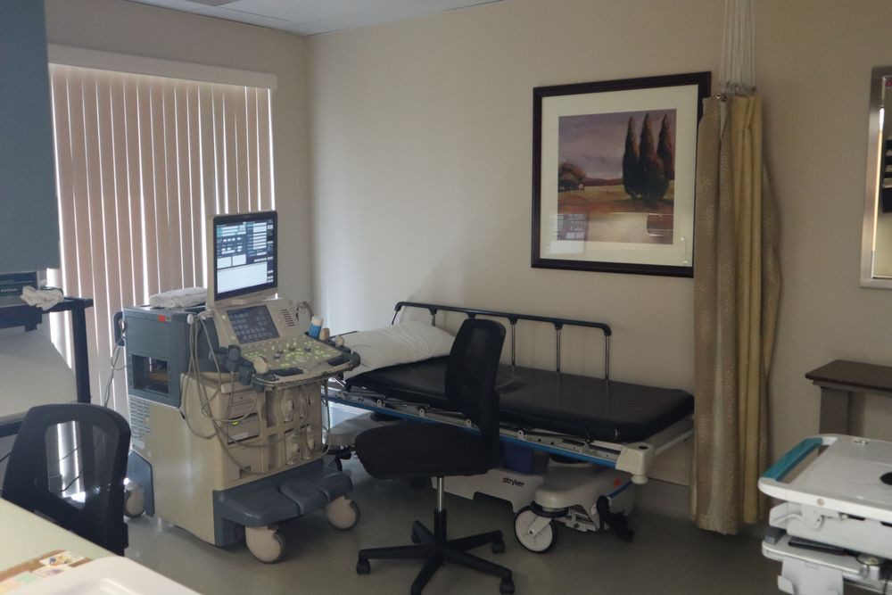 A medical examination room equipped with an ultrasound machine and bed.
