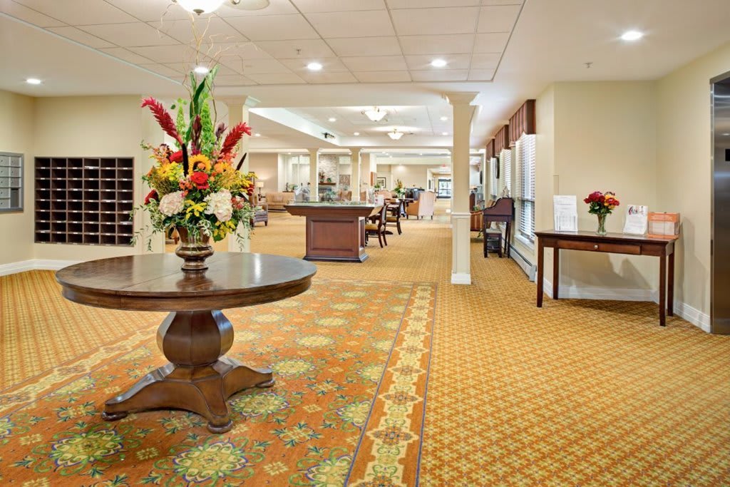 A well-lit lobby area featuring elegant furniture and a floral arrangement on a round table.