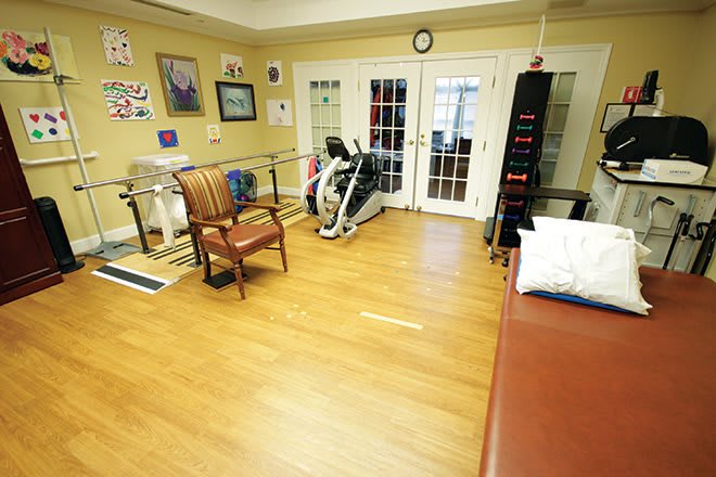 A rehabilitation room equipped with exercise machines and seating, designed for physical therapy sessions.