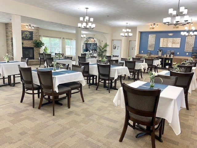 An elegant dining room setup with neatly arranged tables and chairs, featuring chandeliers and tasteful decor.
