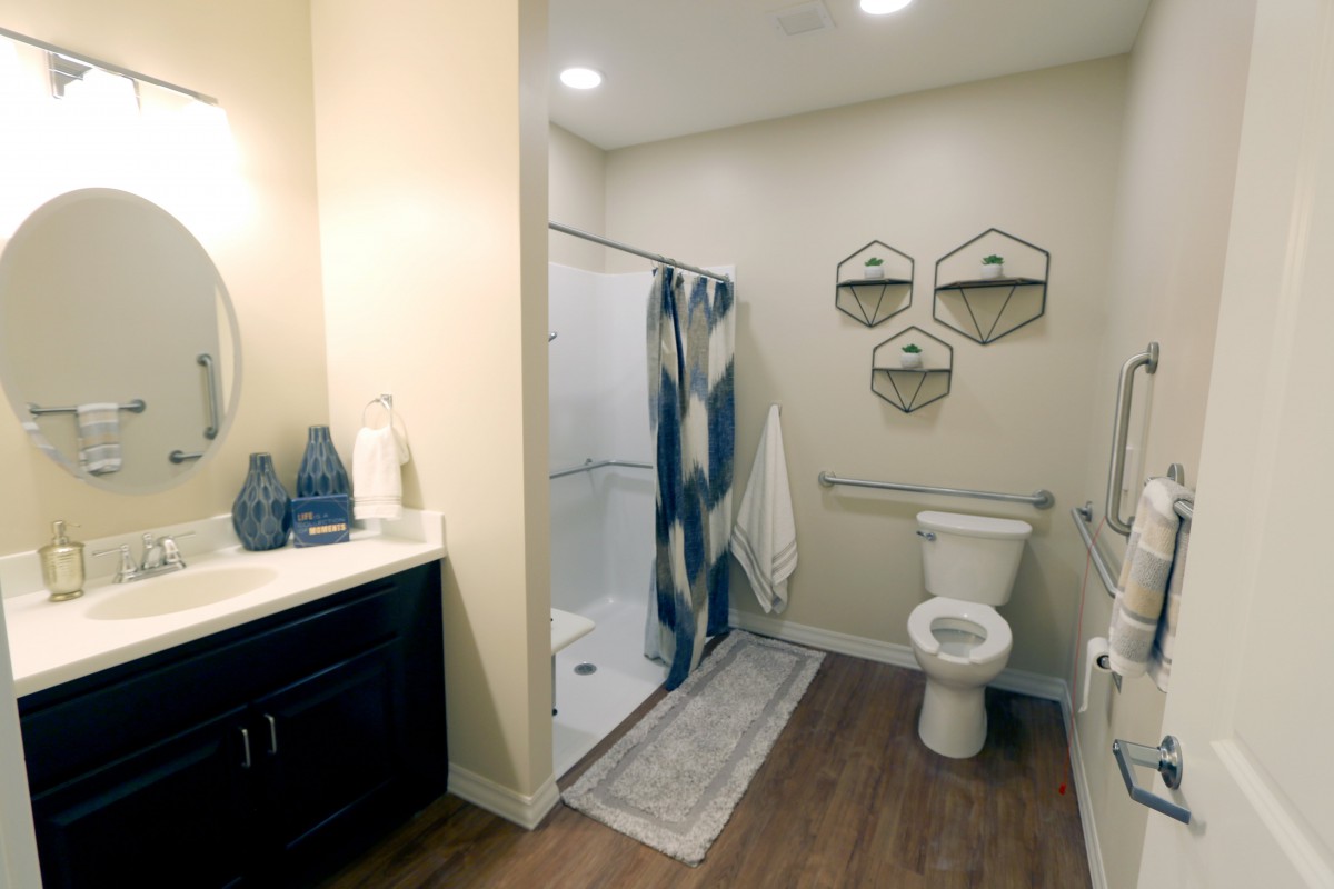 A modern bathroom with a shower, toilet, and sink, featuring decorative elements and warm lighting.