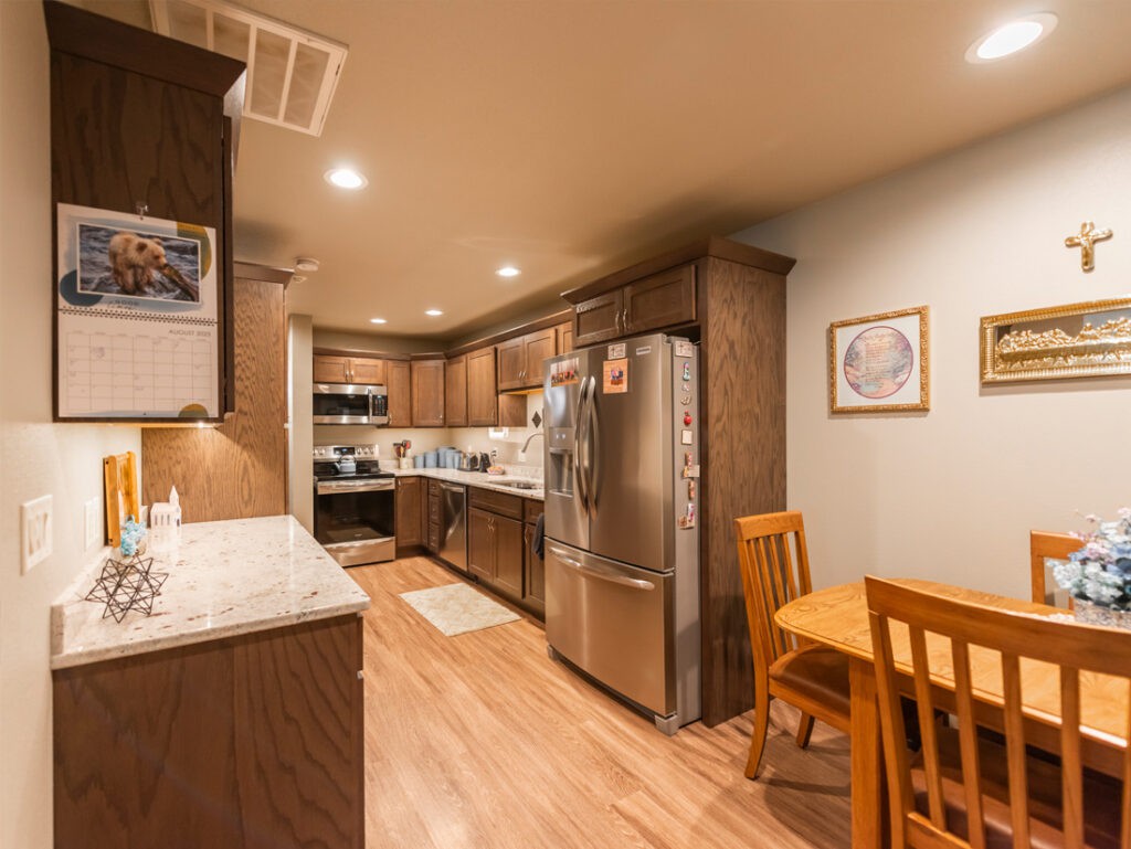A modern kitchen with wood cabinets, stainless steel appliances, and a small dining area.