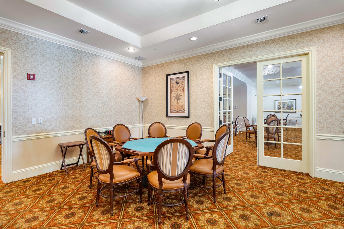 A cozy dining or meeting room with a round table and six chairs, set on a patterned carpet.
