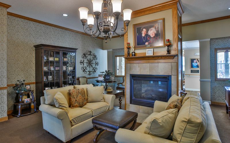 A cozy living room featuring a fireplace, elegant chandelier, and plush sofas.