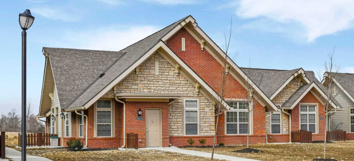 A suburban brick house with a gabled roof and multiple windows.